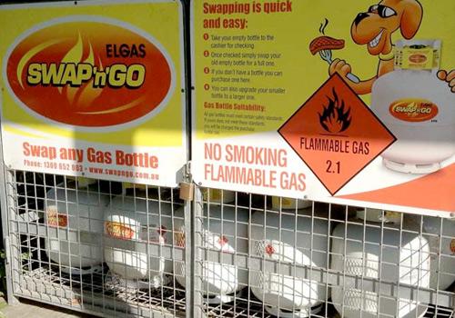 Gas bottle exchange station with signs for Elgas Swap & Go, safety instructions, and a warning about flammable gas